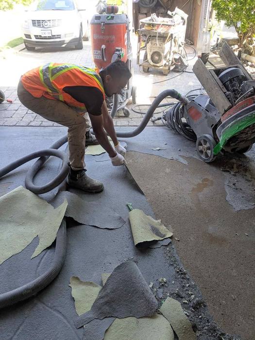Worker grinding down an old garage floor coating before professional epoxy installation